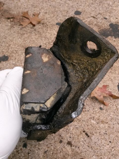 1996 Ford Bronco - A damaged motor mount, likely from a vehicle, is shown close-up on a ground surface.