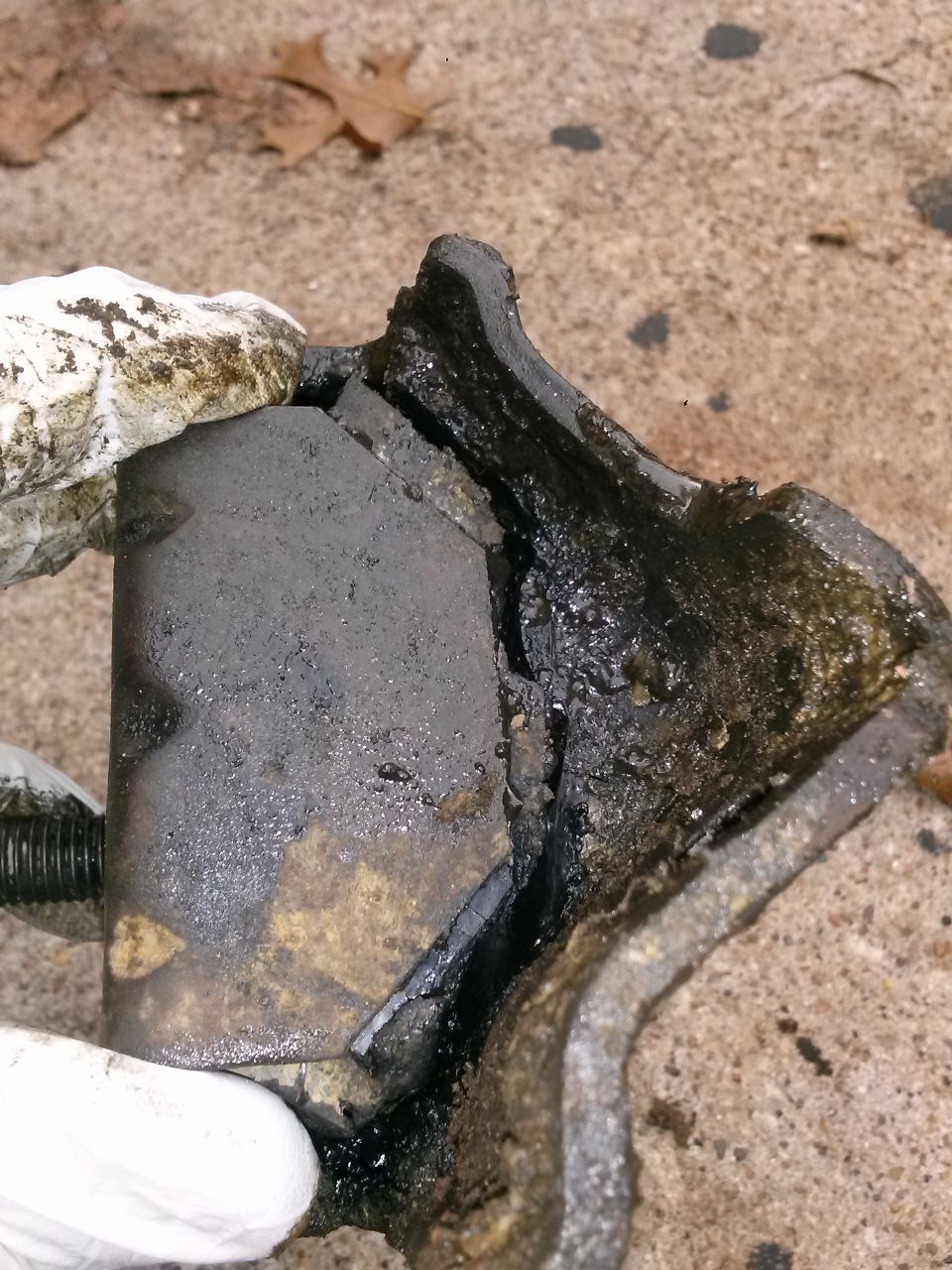 Broken rubber and metal motor mount, covered in grease