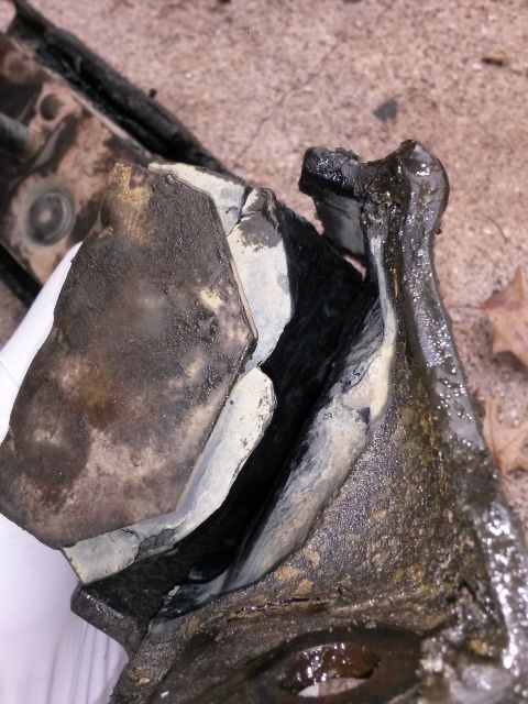 1996 Ford Bronco - This is a damaged automotive part, possibly a motor mount, showing signs of wear and tear.