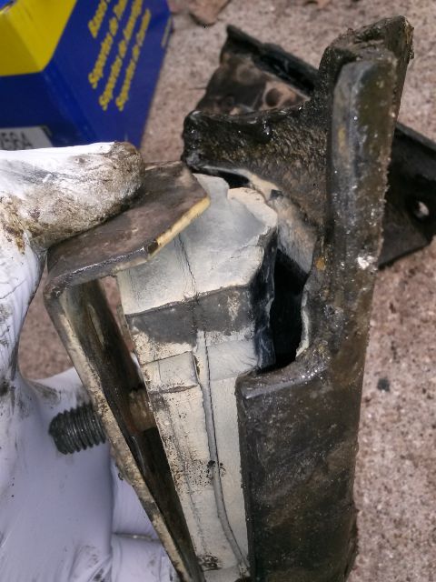1996 Ford Bronco - A heavily worn and damaged engine mount, likely from a 1996 Ford Bronco, is shown. The rubber component is torn and separated from the meta…