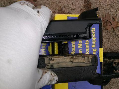 1996 Ford Bronco - A gloved hand holds a black metal part with rubber insulation, resting on a blue and yellow box with text that reads "Mounting Supports".