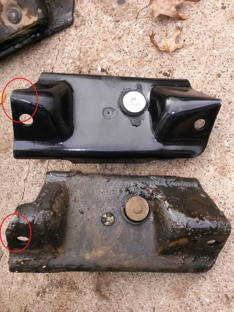 1996 Ford Bronco - Two metal brackets are shown side-by-side on a concrete surface. The top bracket is black and appears new, while the bottom bracket is heav…