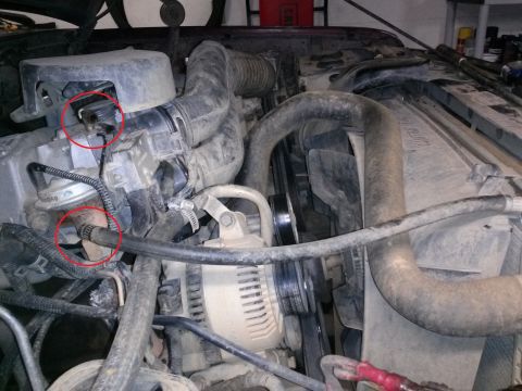 1996 Ford Bronco - A close-up view of the engine bay of a 1996 Ford Bronco, focusing on the intake manifold and associated hoses. Two vacuum hoses are highlig…