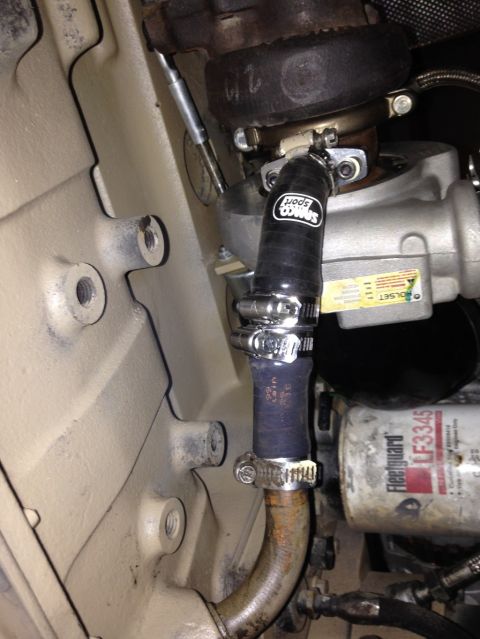1994 Ford Bronco - A close-up view of a black Samco Sport hose connected to a turbocharger on a 1994 Ford Bronco. The hose is secured with metal clamps and a…