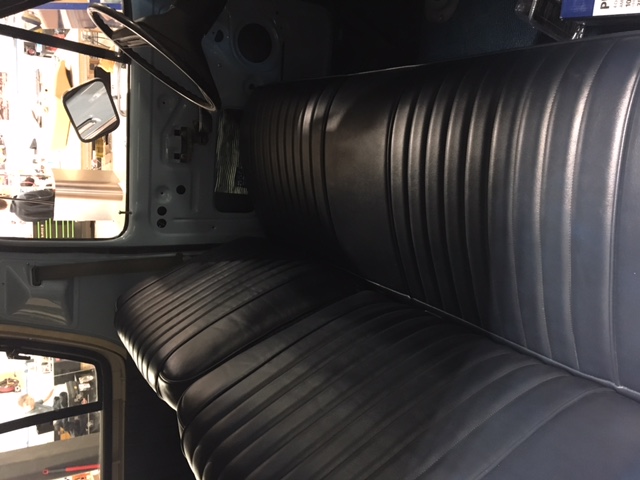Interior of a classic truck or SUV showing a dark blue bench seat and dashboard.