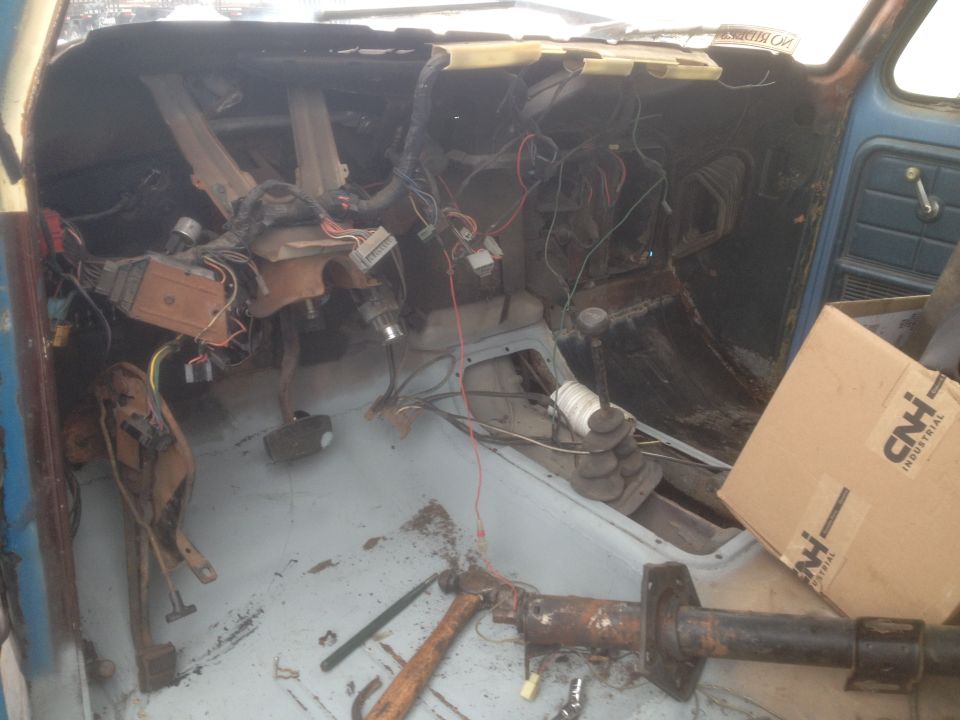 Disassembled interior of a classic vehicle with exposed wiring and a CNH Industrial box.
