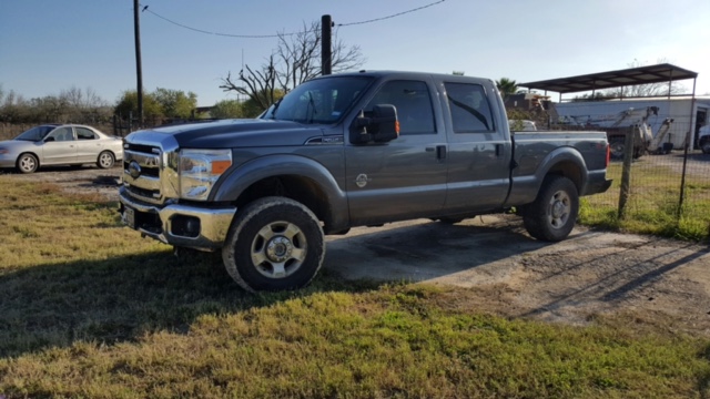 Dark gray Ford pickup truck parked outdoors with a silver sedan in the background.