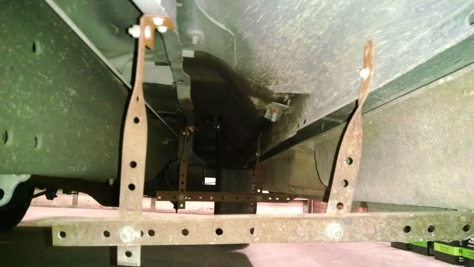 Underside of a vehicle with rusty metal brackets and a spare tire.