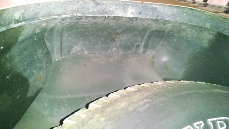 Inside of a vehicle's wheel well showing fender liner and tire.