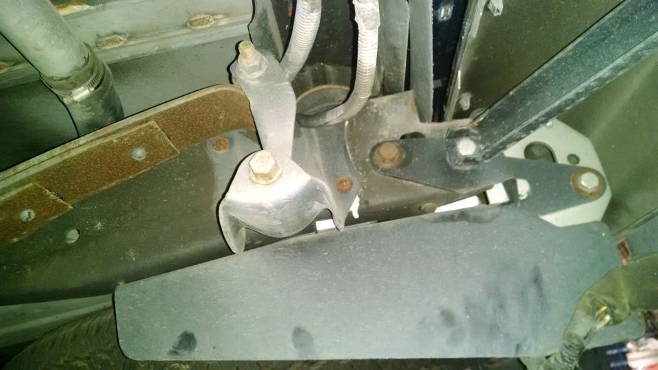 Underside of a vehicle showing suspension, frame, and a hose.