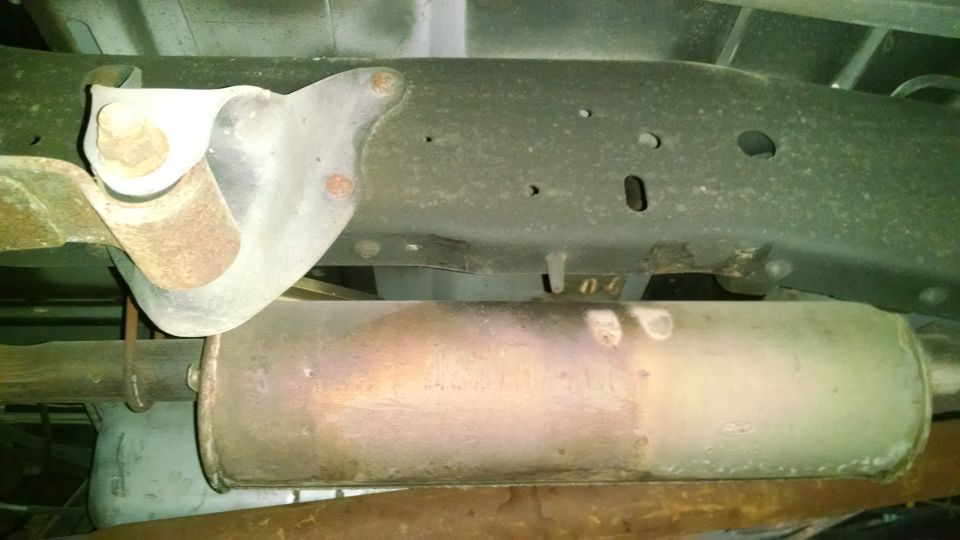 Underside view of a vehicle's exhaust muffler and frame bracket
