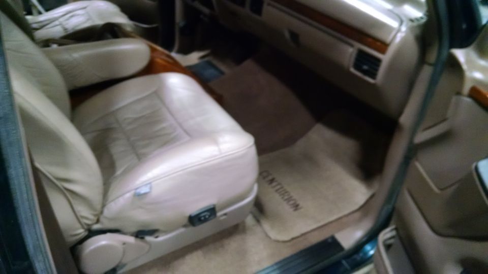 Interior of a vehicle with tan leather seats and a floor mat with the word CENTURION.
