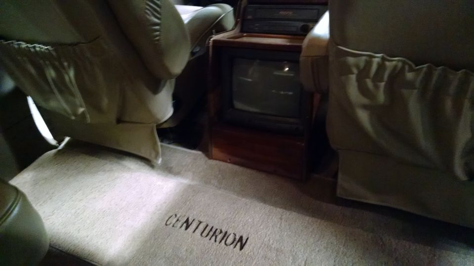 Interior of a vehicle with tan seats and carpet, showing the word CENTURION on the floor.