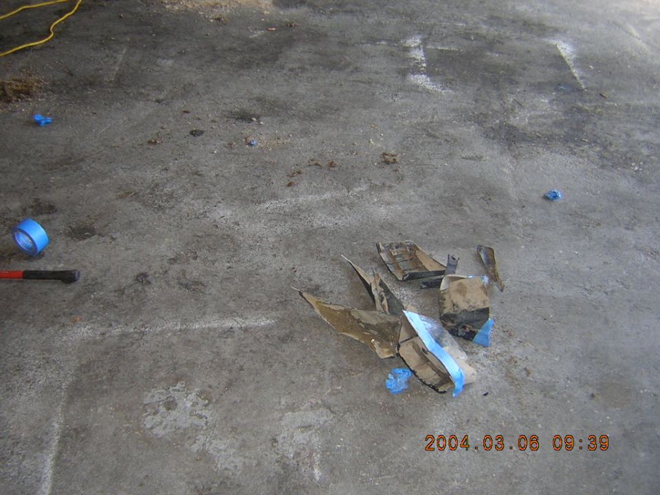 Debris and blue tape on concrete floor with timestamp 2004.03.08 09:39 and Supermotors.net logo