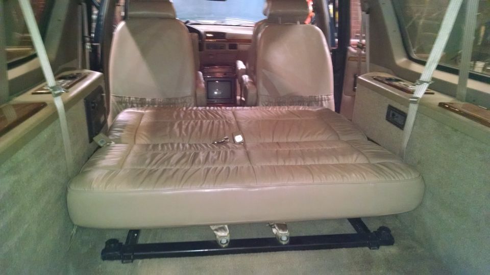 Tan leather fold-down bed in a van interior, with front seats visible
