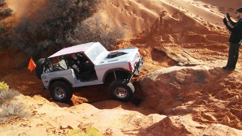 1979 Ford Bronco - A modified 1978 Ford Bronco navigates a challenging off-road course with a person observing.