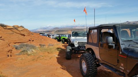 1979 Ford Bronco - A group of Jeeps drives along a desert landscape with a lake and mountains visible in the distance.