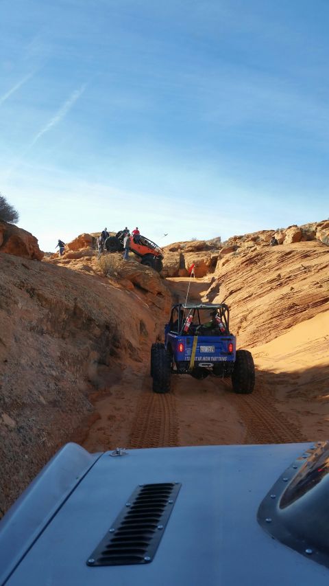 1979 Ford Bronco - Multiple off-road vehicles navigate a sandy canyon under a clear blue sky.