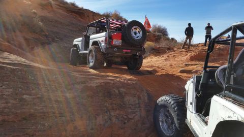 1979 Ford Bronco - Off-roading in a 1979 Ford Bronco on a dusty, rocky trail with another vehicle visible.