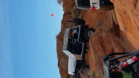 1979 Ford Bronco - Off-road vehicles navigate a challenging rocky terrain under a clear blue sky.