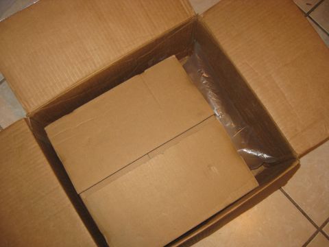 1994 Ford Bronco - A cardboard box contains a part wrapped in plastic, with internal cardboard dividers.