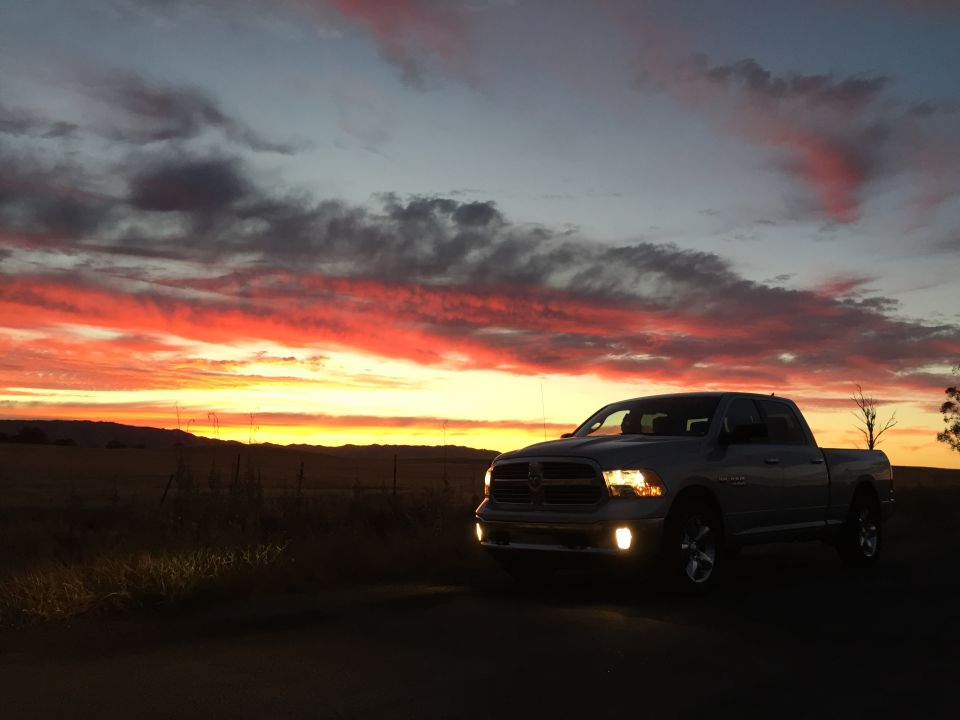 Silver pickup truck parked on a dirt road during sunset