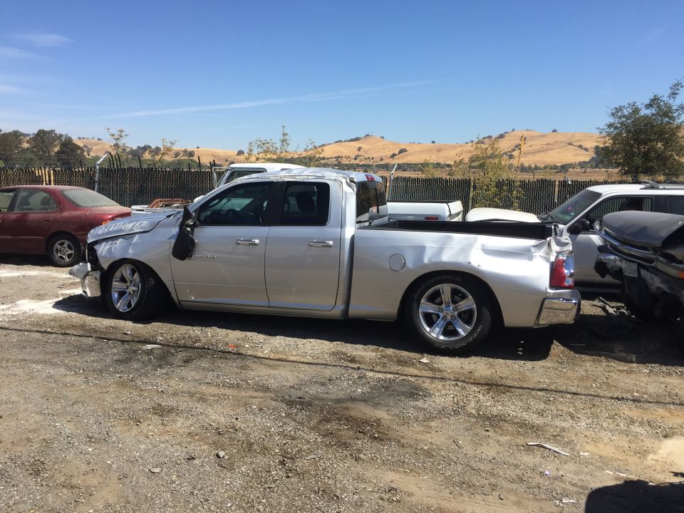 Wrecked silver Dodge Ram quad-cab pickup with front damage in salvage yard