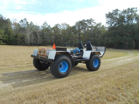 1992 Ford Bronco - This custom-built all-terrain vehicle features large tires with bright blue rims and an exposed engine, viewed from a 3/4 front angle.