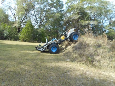 1992 Ford Bronco - An off-road utility vehicle is shown tilted on a grassy incline with trees in the background.