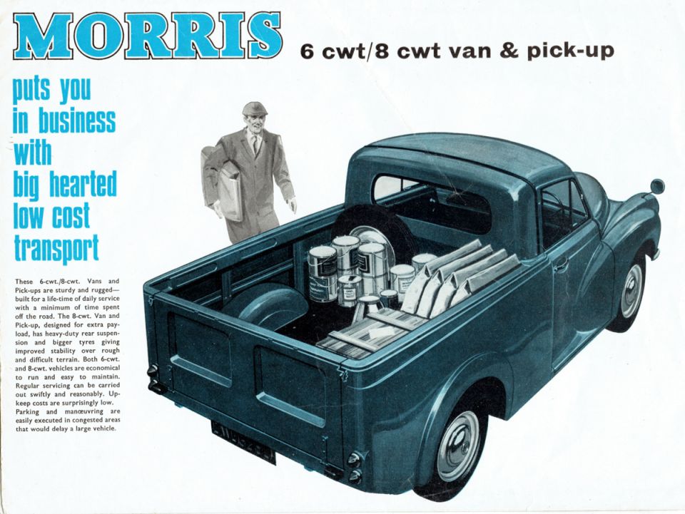 Blue Morris pick-up truck loaded with cans and boxes, with a man standing nearby