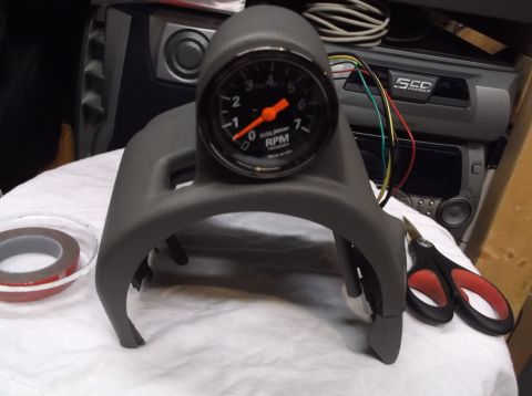 1999 Mercury Grand Marquis - A tachometer gauge is mounted in a gray dashboard trim piece, with installation tools nearby.
