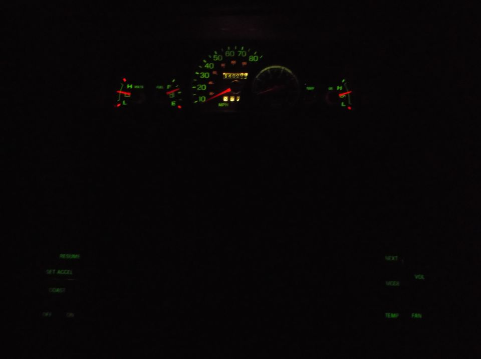 1999 Mercury Grand Marquis dashboard at night, showing illuminated gauges and buttons.