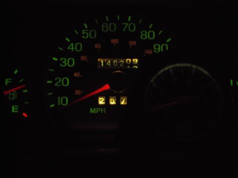1999 Mercury Grand Marquis - The image shows a close-up of a car's dashboard at night, featuring a speedometer with a needle pointing between 20 and 30 MPH, and an odom…