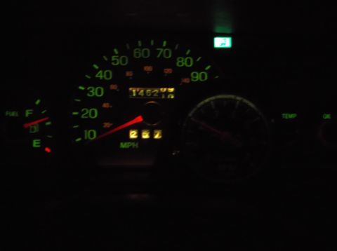 1999 Mercury Grand Marquis - A close-up of a car's dashboard at night shows a lit speedometer with a needle indicating 25 mph and an odometer reading 146210.