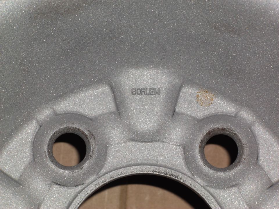 Close-up of a silver alloy wheel with "BORLEM" text and a rust spot.