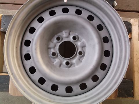 1999 Mercury Grand Marquis - A close-up, overhead view of a silver steel wheel rim. The rim has multiple square cutouts and a central hub with bolt holes.