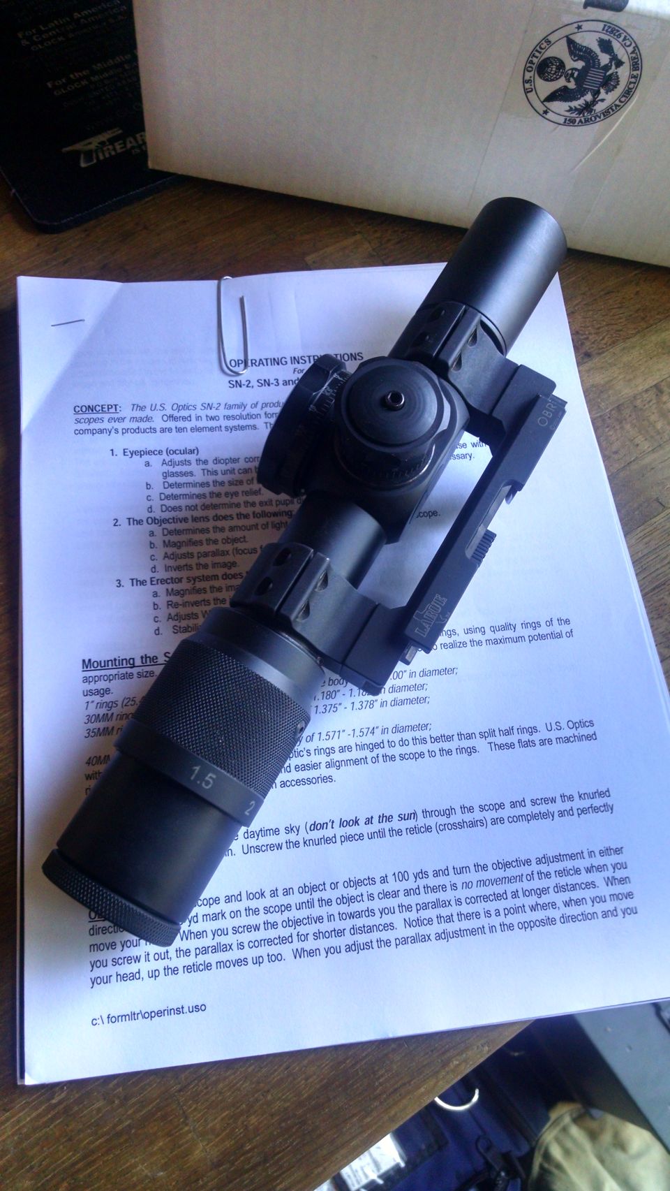 U.S. Optics SN-2 scope on top of its operating instructions manual.