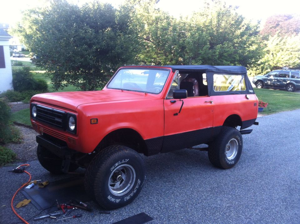 Red 1978 International Scout II with black soft top parked on asphalt driveway.