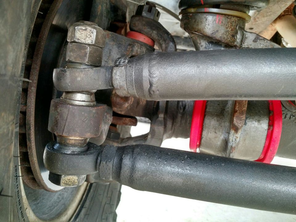 Close-up of a vehicle's steering linkage with red bushings visible