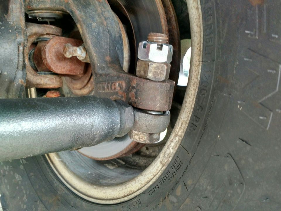 Rusty steering linkage with a tire and brake rotor visible
