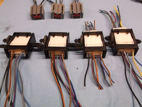 1999 Mercury Grand Marquis - Multiple wiring harness connectors with various colored wires are laid out on a blue surface, with a "SuperMotors" logo visible.
