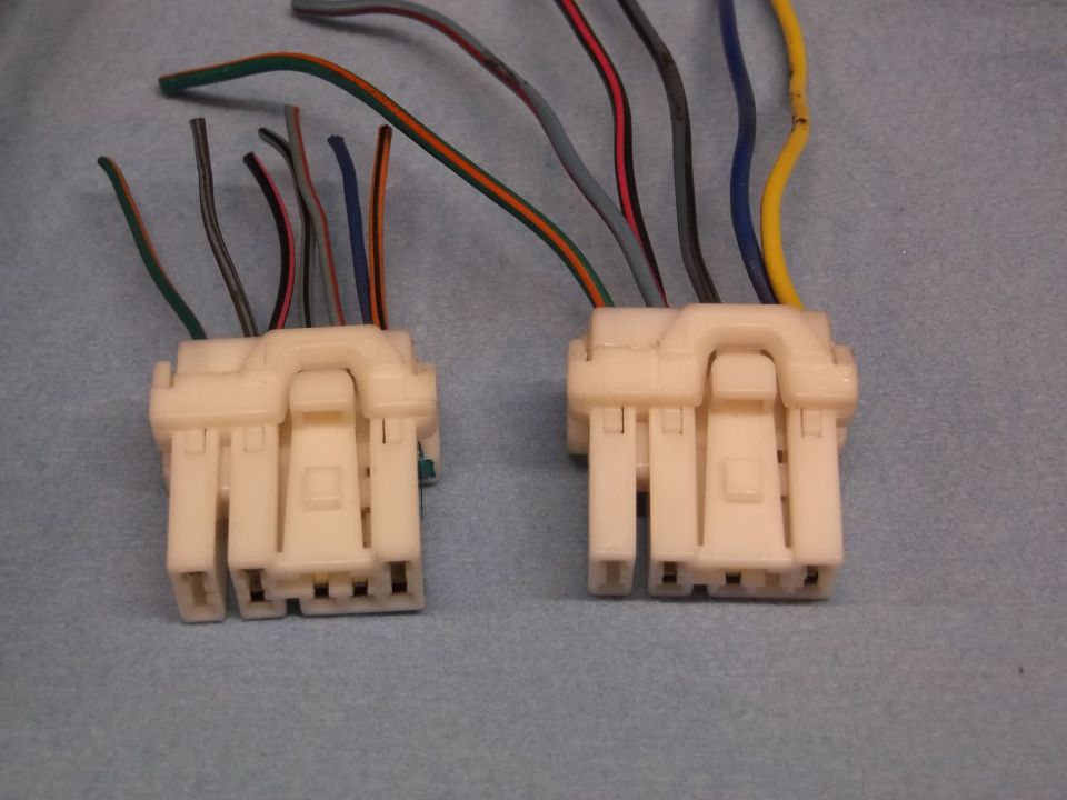 Two white plastic wiring harness connectors with multiple colored wires extending from them