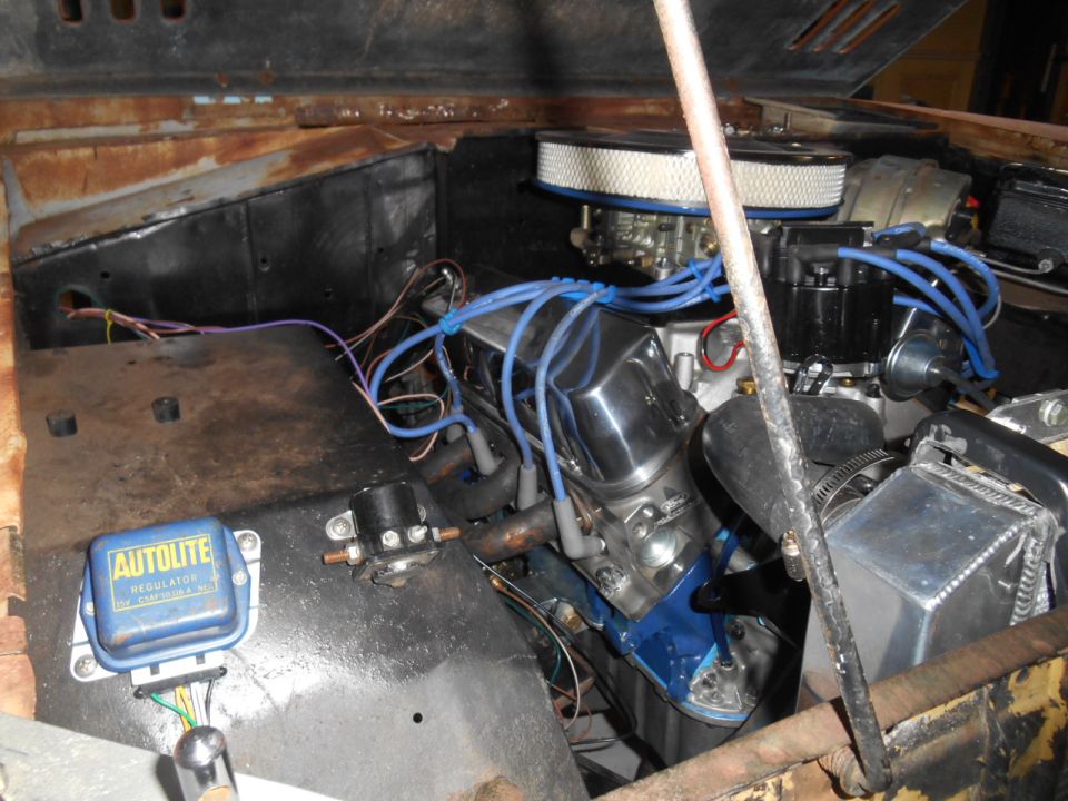 V8 engine in an engine bay with blue plug wires and Autolite regulator