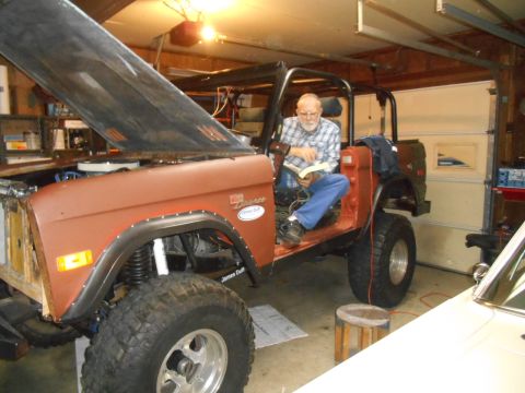 1972 Ford Bronco - A man sits in the driver's seat of a classic Ford Bronco, reading a book while the vehicle is in a garage.