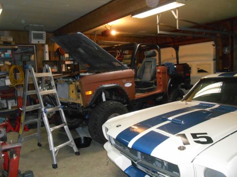 1972 Ford Bronco - A 1972 Ford Bronco is seen in a garage with its hood open, suggesting it is undergoing restoration work. Another vehicle is parked in front…