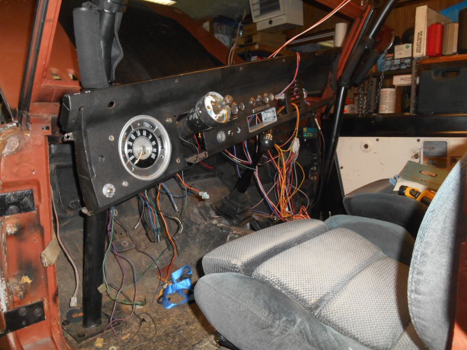 Interior shot of a vehicle's dashboard with exposed wiring and a gauge cluster