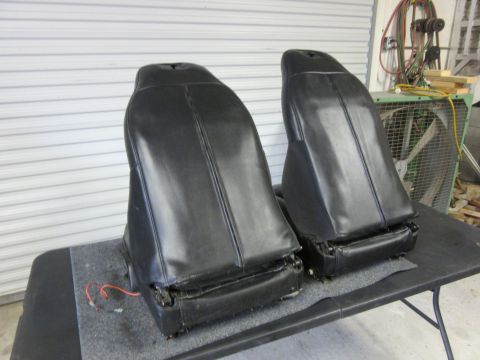Two black car seats on a table, with wiring visible