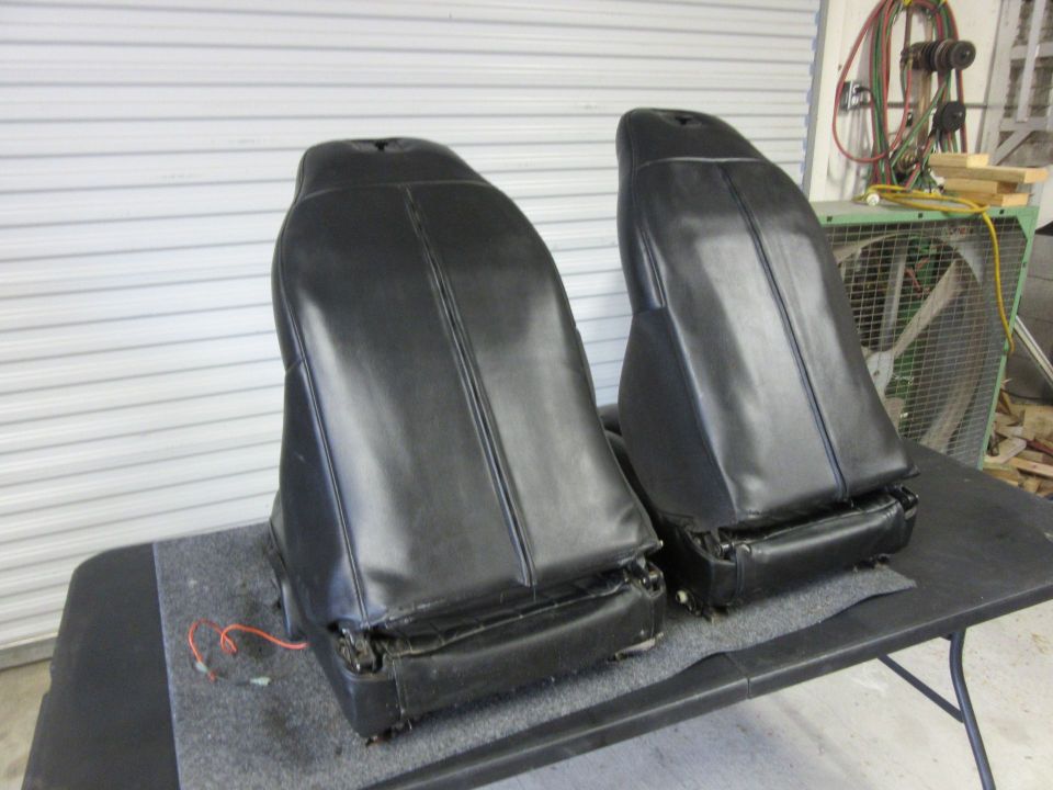 Two black car seats on a table, with wiring visible