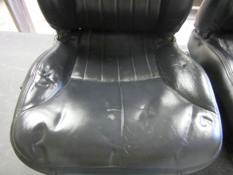 Black leather car seats with vertical stitching and visible wear