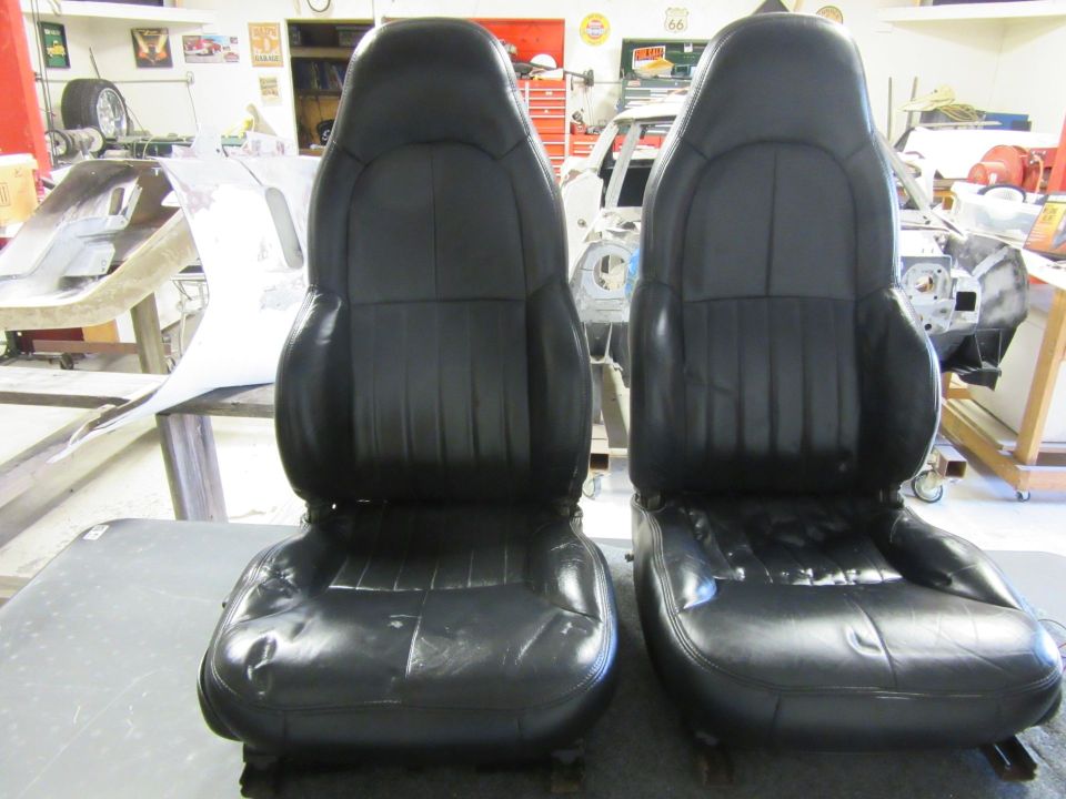 Two black leather car seats, one slightly worn